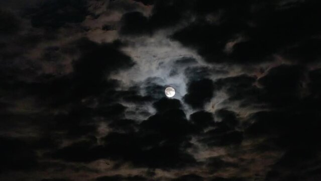 Night cloudy sky with black clouds and full moon. Gloomy night landscape in the moonlight. Midnight on Halloween, real video footage