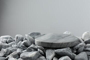 Presentation for product. Stone and pebbles on grey background. Space for text