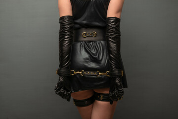Beautiful young woman in a leather dress and bondage set posing back