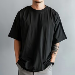 Black oversized t-shirt, cropped and wide sleeves, male model wearing grey pants in the background, front view, in the style of mockup, high resolution photography