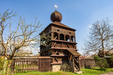 Wooden bell tower belonging to a wooden church in Hronsek, registered as a UNESCO World Heritage Site. Wooden historic bell tower, belfry. Spring atmosphere