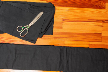 Tailoring Concepts. Cutting Textile Cloth at Work Table With old Rusty Scissors and Black Fabric - 770484241