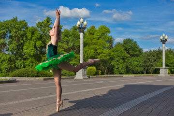 One Flexible Sexy Winsome Caucasian Ballet Dancer in Green Tutu Dress Posing in Dance Pose With Lifted Hands Against Forest