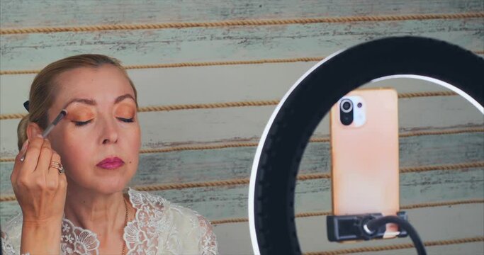 A blonde woman conducts an online master class on applying makeup