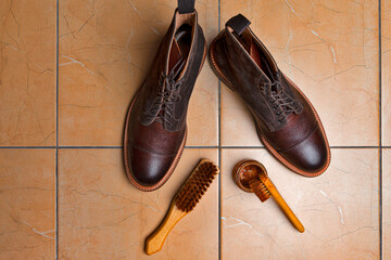 Various Shoes Cleaning Accessories for Dark Brown Grain Brogue Derby Boots Made of Calf Leather Over Tile Background