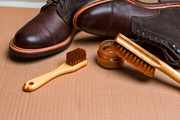 Closeup View of Various Shoes Cleaning Accessories for Dark Brown Grain Brogue Derby Boots Made of Calf Leather Over Tile Background with Special Tools.
