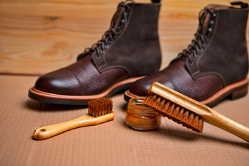 Closeup View of Various Shoes Cleaning Accessories for Dark Brown Grain Brogue Derby Boots Made of Calf Leather Over Paper Background
