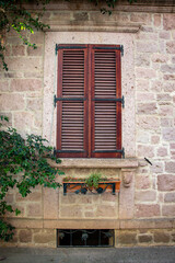 Fototapeta na wymiar Vintage window with shutters on the wall of an old house..window in Cunda Turkey old construction and wood the historical