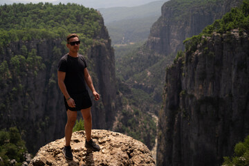 Man enjoys canyon amid green rocky mountains. Perfect for adventure tours, expeditions, and...