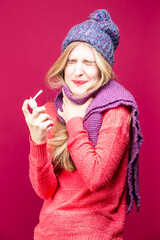 One Depressed Young Caucasian Female With Sore Throat Using Spray Inhaler for The Infection Protection and Disinfection With Knitted Hat and Scarf - 770488211