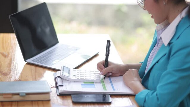 Asian Businesswoman working with calculator and laptop at the office.