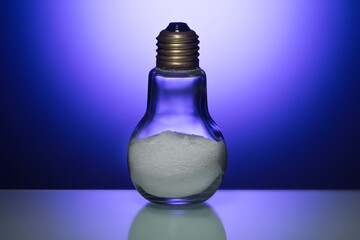 Composite Image of Glass Bulb Lamp Filled with Salt Powder Over Glowing Blue Background