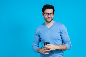 Smiling Caucasian Handsome Brunet Man With Brown Paper Disposable Cup Posing in Glasses And Looking Straight Against Blue