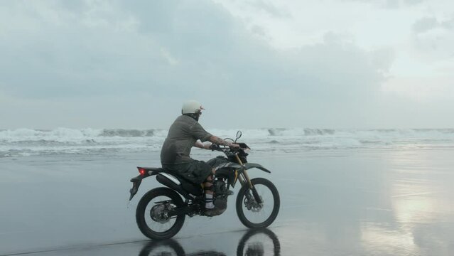 Man biker driving his bike motorbike beside the natural ocean beach.
