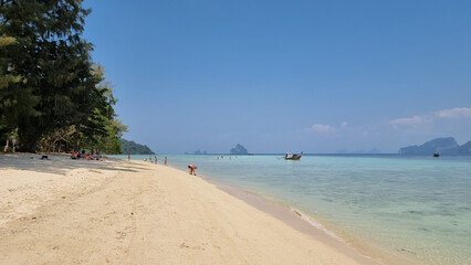 A tranquil sandy beach with a colorful boat peacefully floating in the crystal-clear water