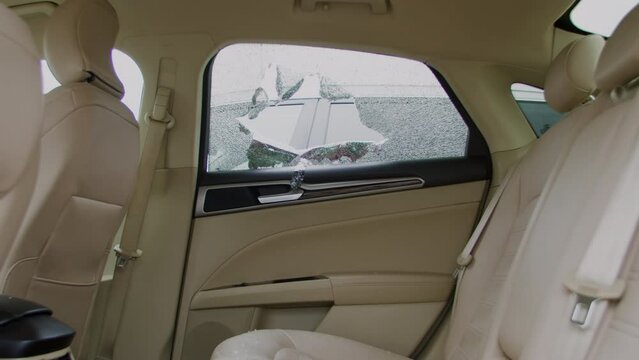 Criminal car thief smashes car window to steal it. Thief shatters car window intent on stealing it Sound of breaking glass echoes through silent as burglar strikes to gain access to automobile.
