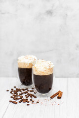 Black coffee with whipped cream on a light wooden table. 