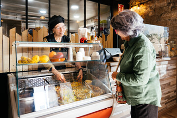 Senior Woman Purchasing Food at a Takeaway Counter During the Daytime