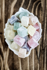 Colorful Pastel Turkish Delights in a Shallow White Bowl on a Dark Brown Wooden Background