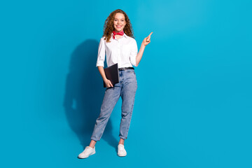 Photo portrait of pretty young woman point empty space netbook dressed stylish white clothes isolated on blue color background