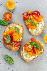 Toast, snack, bruschetta, sandwich with cream cheese, peaches, tomatoes and green basil leaves, Concept healthy and balanced eating, top view