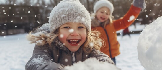 Two toddlers are happily playing in the freezing snow, building snowmen with carrot noses, coal smiles, button eyes, and twig arms