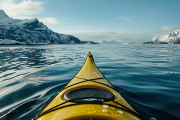 Foto auf Acrylglas A yellow kayak glides through the tranquil arctic sea, with majestic snow-capped mountains as a backdrop. © Philipp