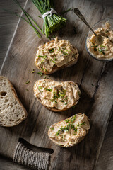 Close-up of bread slice with traditional Slovak bryndza spread made of sheep cheese with freshly cut chives placed on rustic wood
