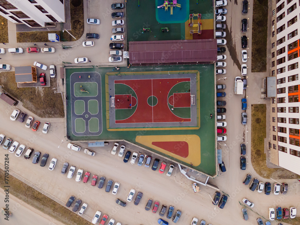 Poster top view of a football field, parking with cars, a playground covered with a green rubber modular co