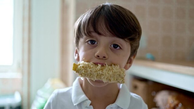 Little Boy Facing The Camera Holding A Devoured Cooked Corn Cob In His Mouth