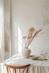Neutral toned table setting with dried pampas grass decoration and soft lighting.