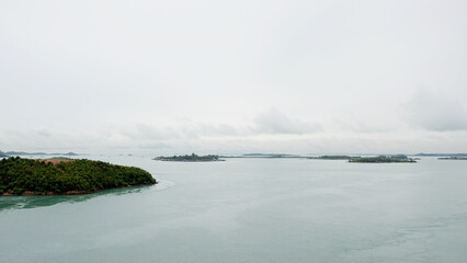 Groups of small islands stretched into the far horizon, with calm sea and gloomy sky. View from on top of Barelang Bridge, Indonesia.
