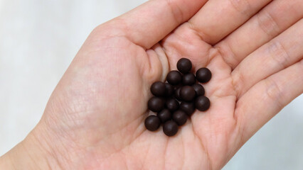 Palm with a small pile of traditional Chinese medicine in small black balls. 