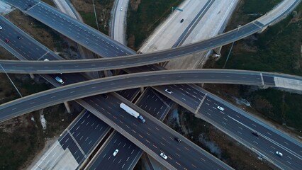 Cars driving along freeway go to exits from multi-level interchange. Top view from drone. Modern design of American transportation system: aerial perspective of multi-level interchange