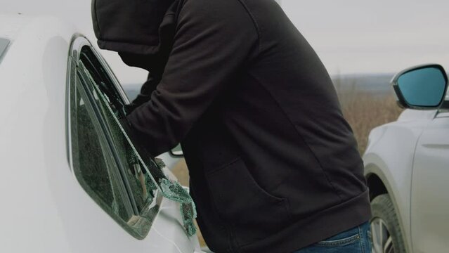 Car thief swiftly snatches backpack from vehicle silent intrusion marked by shattered glass. Crime scene stolen belongings vanish into streets Perpetrator leaves trail of deceit and violation.