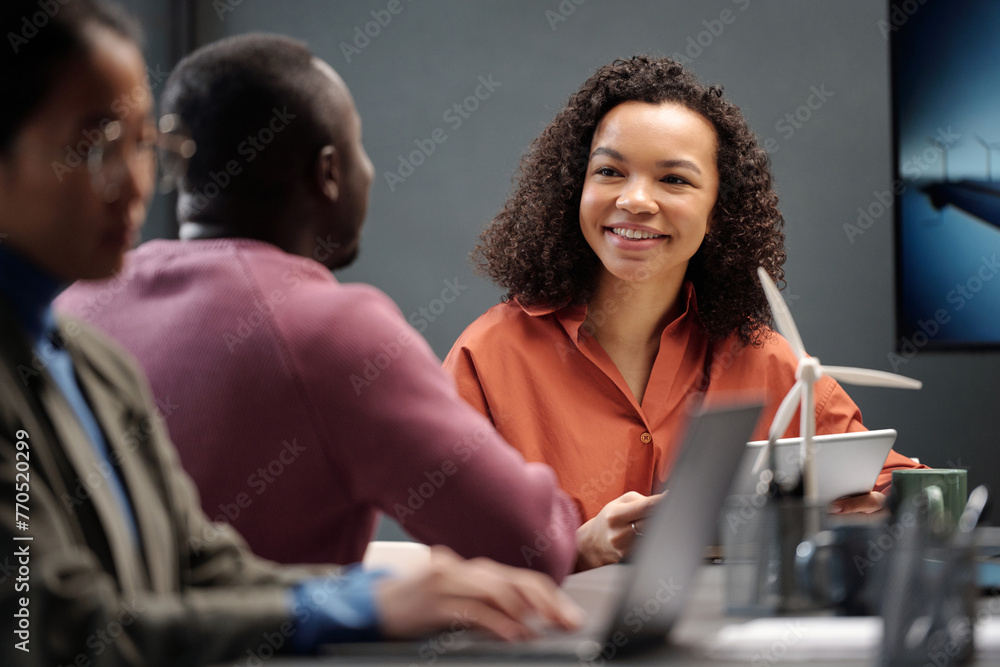Poster young smiling businesswoman looking at male colleague during discussion of project points while maki