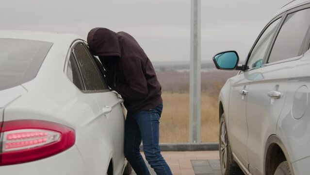 Carjacker in hoodie cracks open and hijacks vehicle. Carjacker proficient in auto theft and hacking commanders stolen car Car now under control of carjacker leaving behind only empty space.