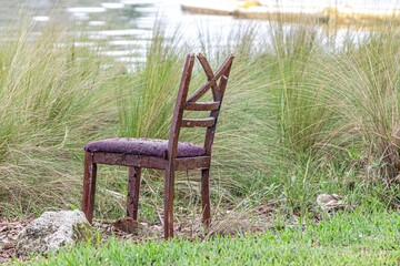a chair sitting on top of a lush green field next to a pond