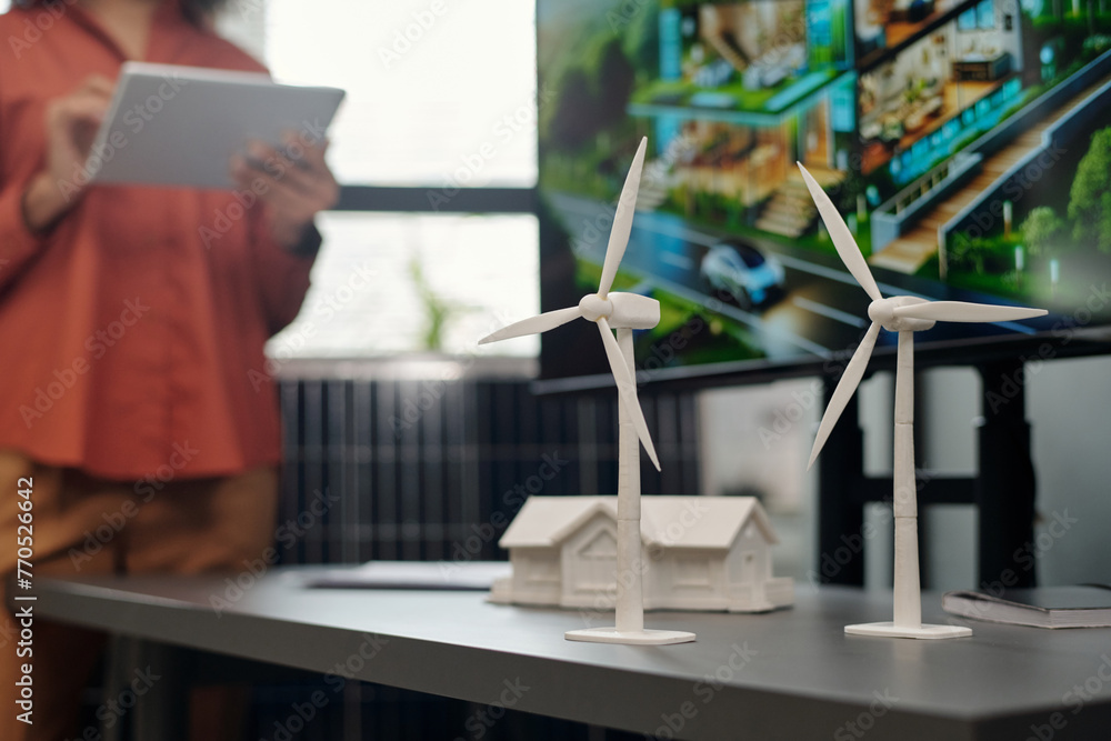 Poster Two windmill models standing on grey desk next to plastic house mockup and interactive board with visual template of new business project