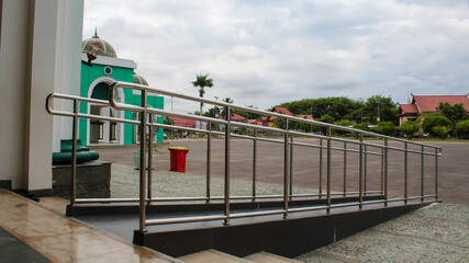 Wheelchair ramp with stainless steel handrail at the main entrance of a mosque.