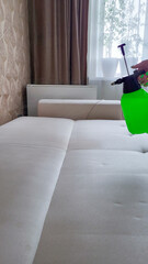 A professional sprays cleaning agent on a white orthopedic sofa to remove stains