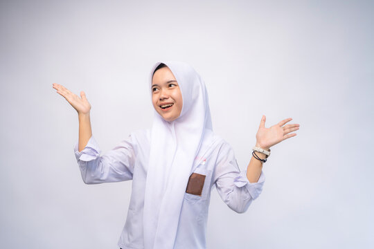 Happy Female Indonesian high school student in white and grey uniform at Copy Space Advertising Your Text, Standing Isolated Over white Studio Background