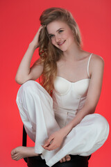 Portrait of blond young woman sincerely smiling, sitting on bar stool with her feet up on it and...