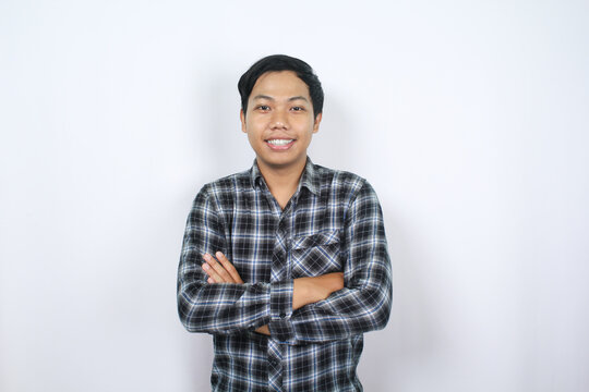 optimistic asian man smiling at camera with folded arm isolated