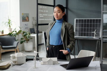 Young confident Asian businesswoman in formalwear looking at camera during work over new architectural project in openspace office - obrazy, fototapety, plakaty
