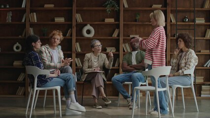 Diverse participants in a group therapy session engage in a discussion with a professional counselor leading the conversation