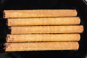 Wafer tubes with chocolate cream on black dish, top view
