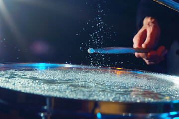 Close-up of drum with water drops jumping from stick's strike. Creative and impressive live...