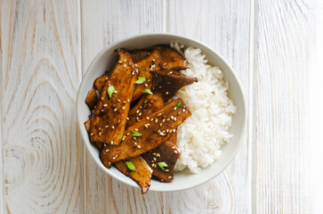 Eryngii mushroom fried with sesame and green onion and white boiled rice in a gray bowl. Dishes Gochujang King Oyster Mushrooms. Traditional Korean cuisine. Horizontal orientation. Top view
