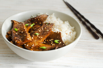 Eryngii mushroom fried with sesame and green onion and white boiled rice in a gray bowl. Dishes...